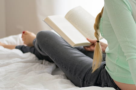 woman sitting on bed while reading book thumbnail
