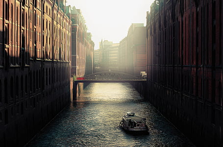 boat in canal in between high-rise buildings thumbnail