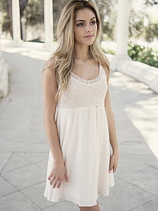woman wearing beige minidress standing on grey concrete pathway thumbnail