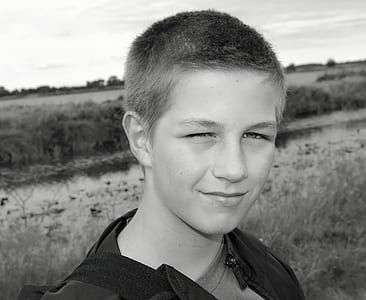 grayscale photo boy standing near river thumbnail