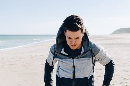 man in grey and black hooded jacket walking on beach thumbnail