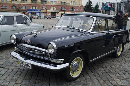 parked classic sedan near people standing thumbnail