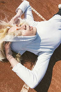 Woman Wearing Pull over Hoodie Laying on Brown Carpeted Floor thumbnail