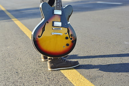 person carrying brown electric guitar thumbnail