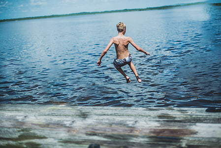 boy jumping towards blue sea thumbnail