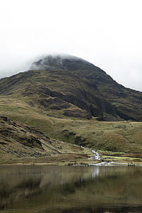 mountain covered with fog beside body of water thumbnail