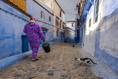 person in purple suit carrying black plastic pail thumbnail
