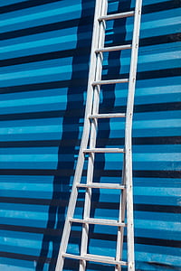 gray step ladder learning on blue roll-top door thumbnail