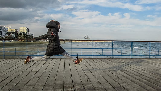 person leaping on wooden platform near beach thumbnail