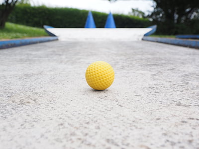 yellow golf ball on concrete road thumbnail