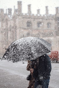 two people sharing black umbrella with snow's pouring selective focus photography thumbnail