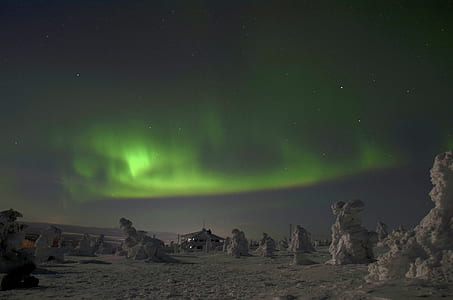 lighted gray house surrounded by gray rock formations under Aurora Borealis thumbnail