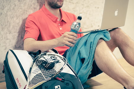 man sitting on brown wooden surface while holding Gatorade plastic bottle thumbnail
