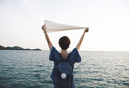 man standing near body of water holding white textile during daytime thumbnail