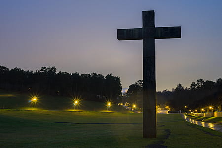 Brown Cross Statue on Green Grass Field With Turned on Light during Nighttime thumbnail