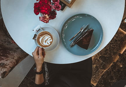 person holding a cup of coffee with sliced cake on side thumbnail