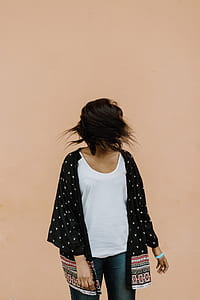 standing woman flipping her hair in front of brown wall thumbnail