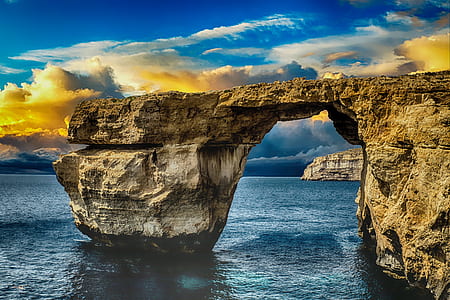 gray rock formation on seashore under blue sky thumbnail