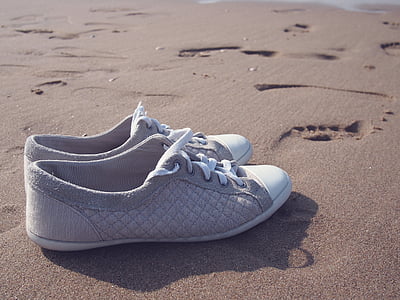 pair of gray-and-white low-top sneakers on sand at daytime thumbnail