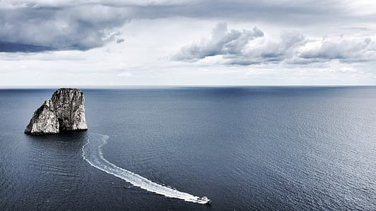 aerial photography of speedboat near rock island thumbnail