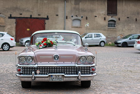 classic pink vehicle parked near brown bricked building at daytime thumbnail