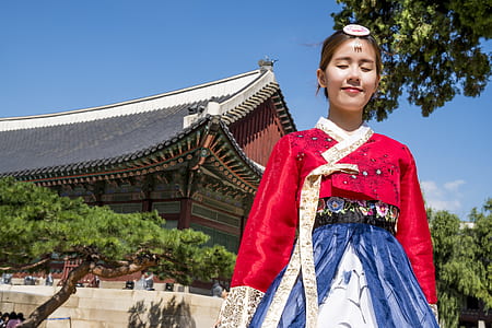 woman wearing red and blue kimono with brown building in background during daytime thumbnail