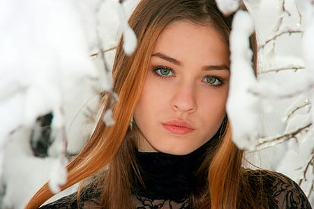 woman in black lace turtleneck top standing near white snow-covered tree thumbnail
