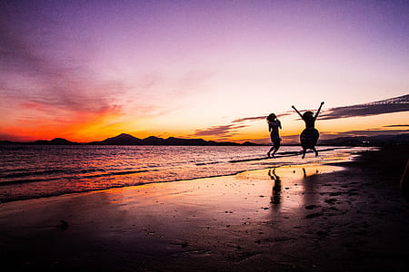 two person jumps beside beach thumbnail