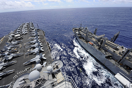 Air Force ship with jet planes beside small white battle ship on sea water during daytime thumbnail