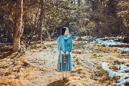 woman wearing teal dress standing on brown grass area thumbnail