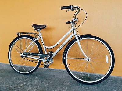 white and grey cruiser bike leaning on orange painted wall thumbnail