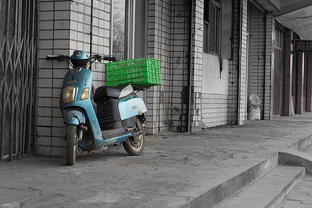 focus photography of blue motor scooter leaning on wall thumbnail