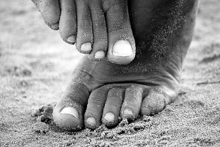 grayscale photograph of person's foot stepping on sand thumbnail