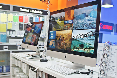 two turned on silver iMac monitors on white wooden desk thumbnail