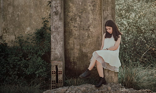 Woman Sitting on Slab Near Brown Wall thumbnail
