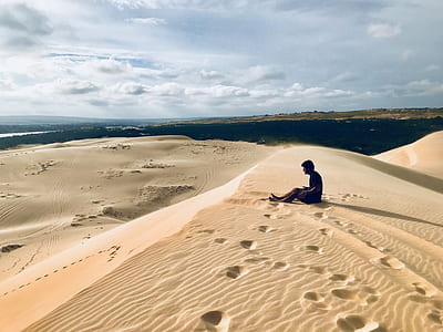man sitting on desert sand thumbnail