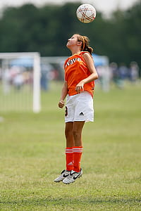 girl bouncing ball on her head on field thumbnail