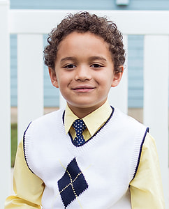 boy wearing sweater vest near wooden fence at daytime thumbnail