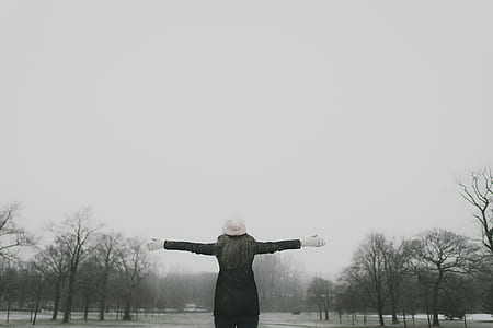 woman wearing black jacket and white hat standing near road during noontime thumbnail