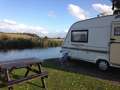 white Hurricane camper trailer parked beside body of water and green grass during daytime thumbnail