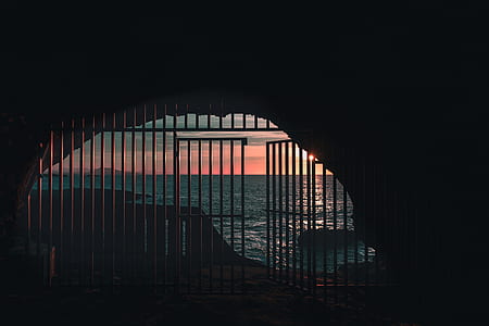 silhouette of gate near body of water thumbnail