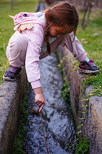 girl wearing pink and white unicorn onesie playing in canal thumbnail