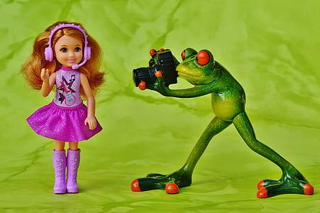 frog holding camera beside girl doll thumbnail