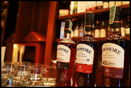 three Owmore bottle on table near clear shot glasses thumbnail