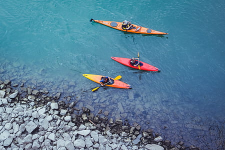 three red kayak floating on body of water thumbnail