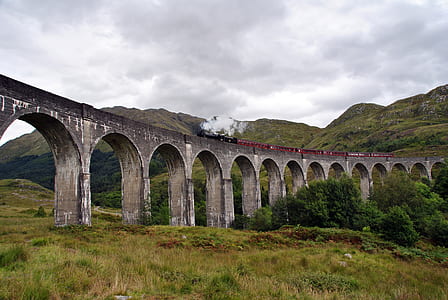 train on concrete rail ways surrounded by mountains thumbnail