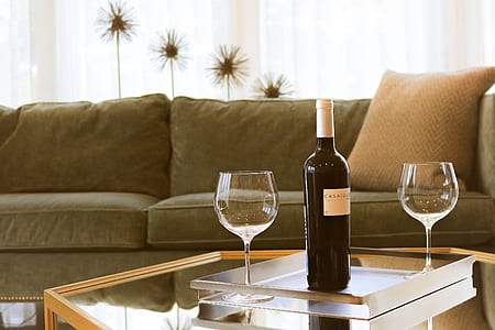 wine bottle and two wine glasses on table inside room thumbnail