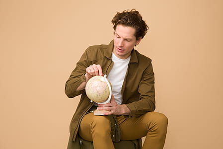 man sitting on chair holding brown table globe thumbnail