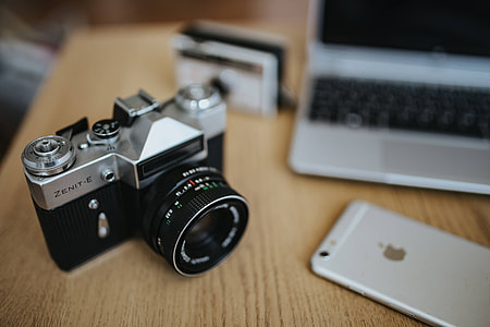 Old Zenit camera and a Canon camera with black-and-white photos on a wooden table thumbnail