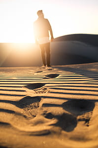 man standing on brown sand with sand dunes as back drop thumbnail